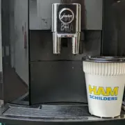 Koffiebeker onder koffiemachine met logo