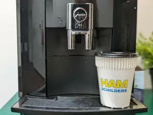 Koffiebeker onder koffiemachine met logo