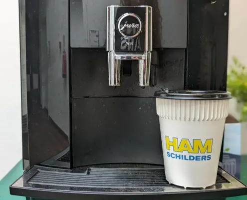 Koffiebeker onder koffiemachine met logo