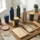 Houten bureau met duurzame cadeaus: herbruikbare waterflessen, koffiemokken en kantooraccessoires met planten