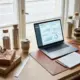 Duurzame waterflessen en koffiemokken op houten bureau met analytics dashboard op laptop en zakelijke cadeaus