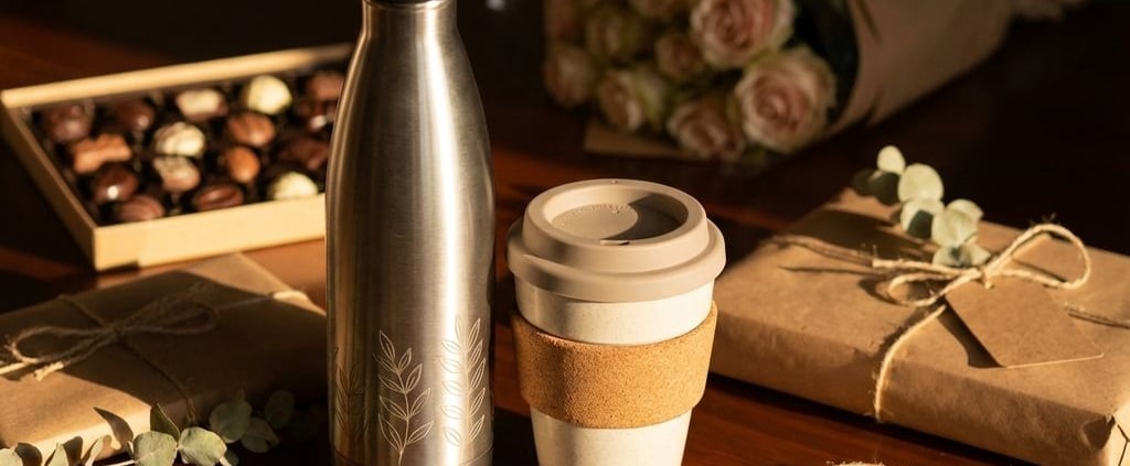 Duurzame cadeaus op houten tafel: herbruikbare waterfles en koffiebeker in warm licht, traditionele cadeaus op achtergrond