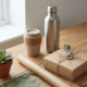 Duurzame relatiegeschenken op houten bureau: RVS waterfles, herbruikbare koffiebeker en eco-vriendelijke verpakking