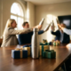 Stalen waterfles op vergadertafel met cadeaudozen en linten, collega's proosten op achtergrond in kantoor