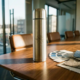 Elegante roestvrijstalen thermosfles met laseretching op gepolijste houten vergadertafel met kleurstalen en stoffenmonsters