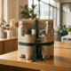 Ingepakte roestvrijstalen waterflessen en geïsoleerde koffiebekers op een eikenhouten bureau, versierd met eucalyptus in warm ochtendlicht.